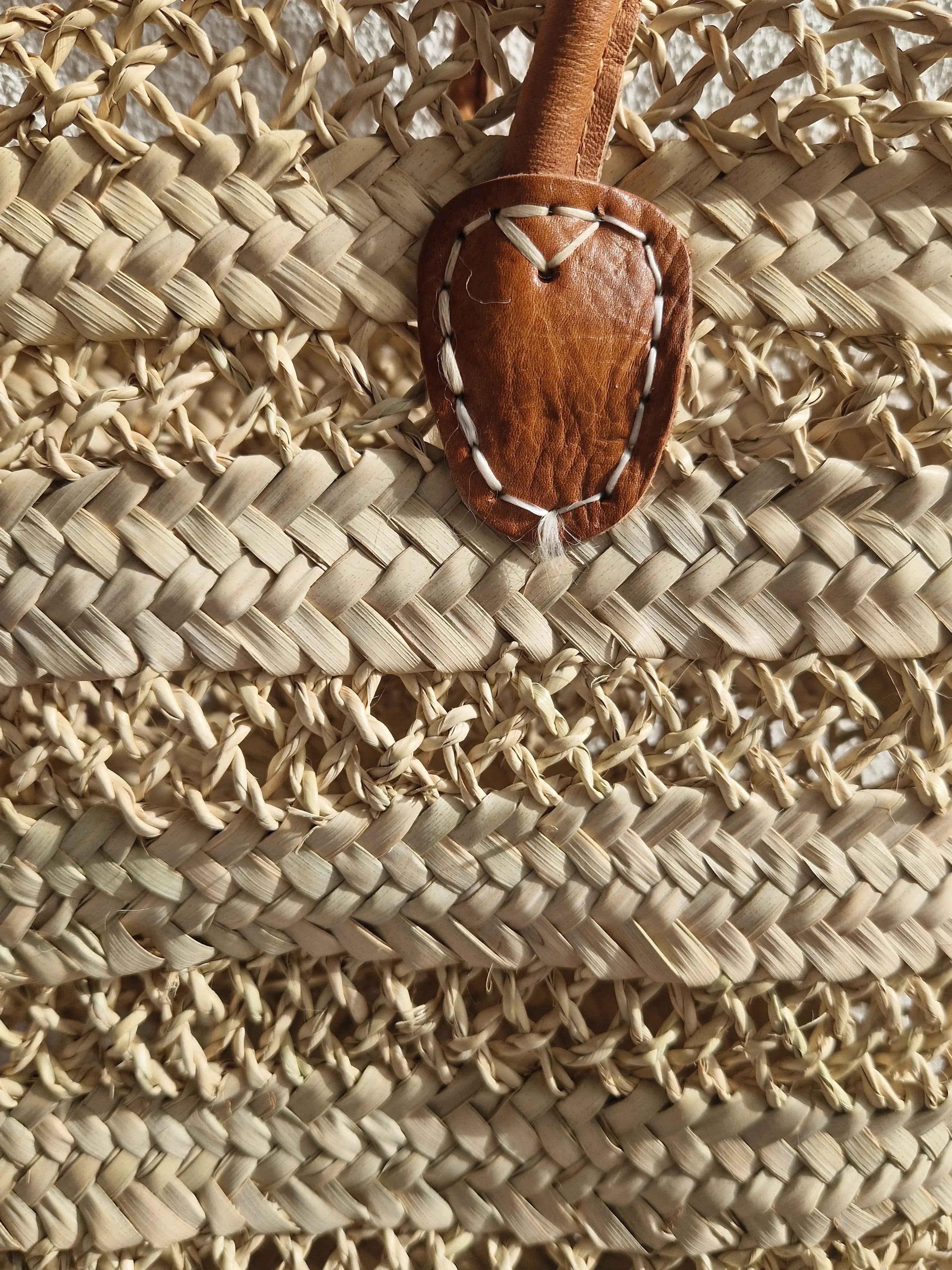Panier en feuille de palmier artisanal marocain, design ajouré avec anses cuir. Idéal comme cabas de marché, sac de plage ou panier bohème chic.