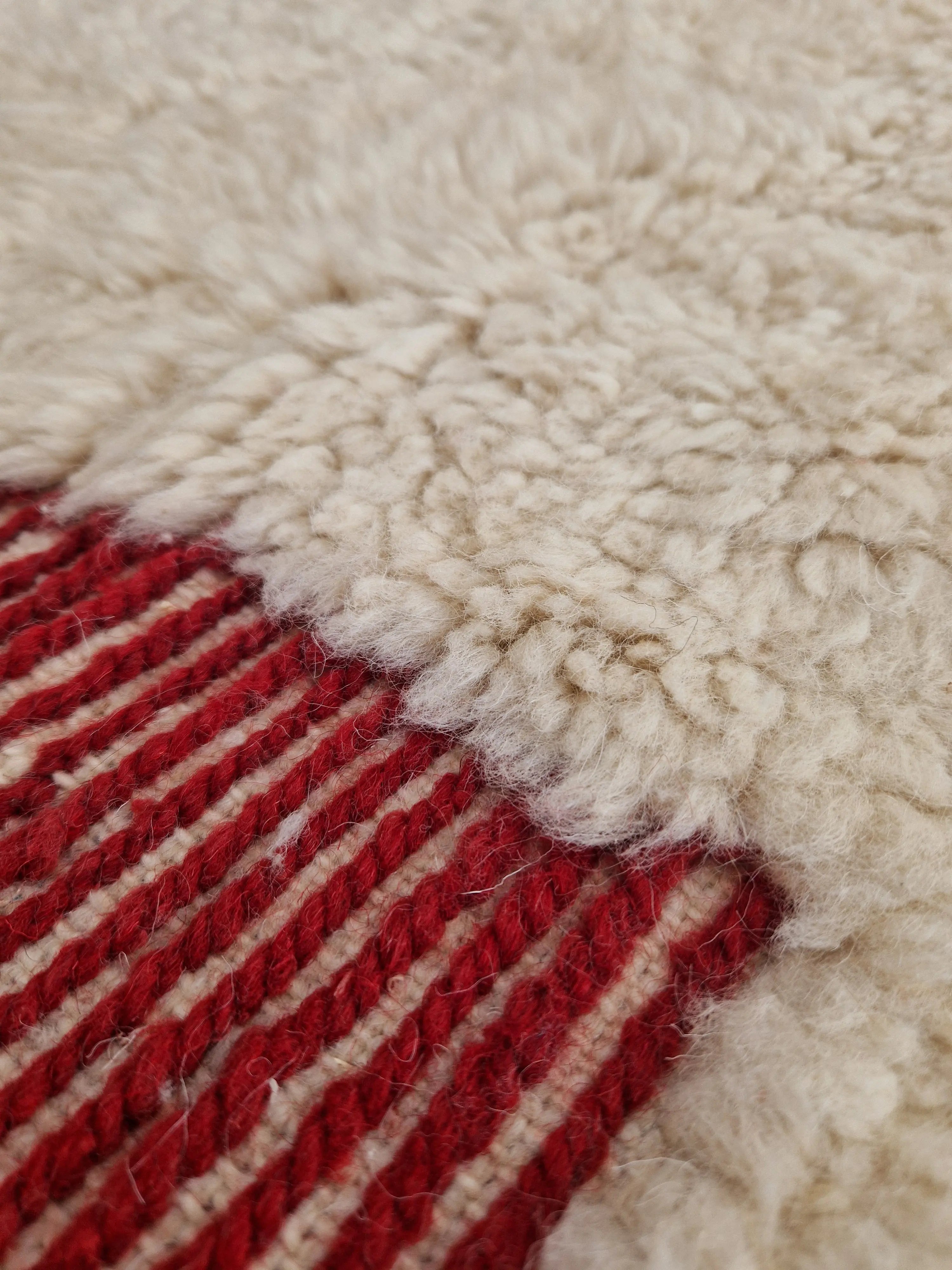 Tapis berbère beni ouarain noué à la main par des artisans marocains, aux motifs géométriques rouge en relief,