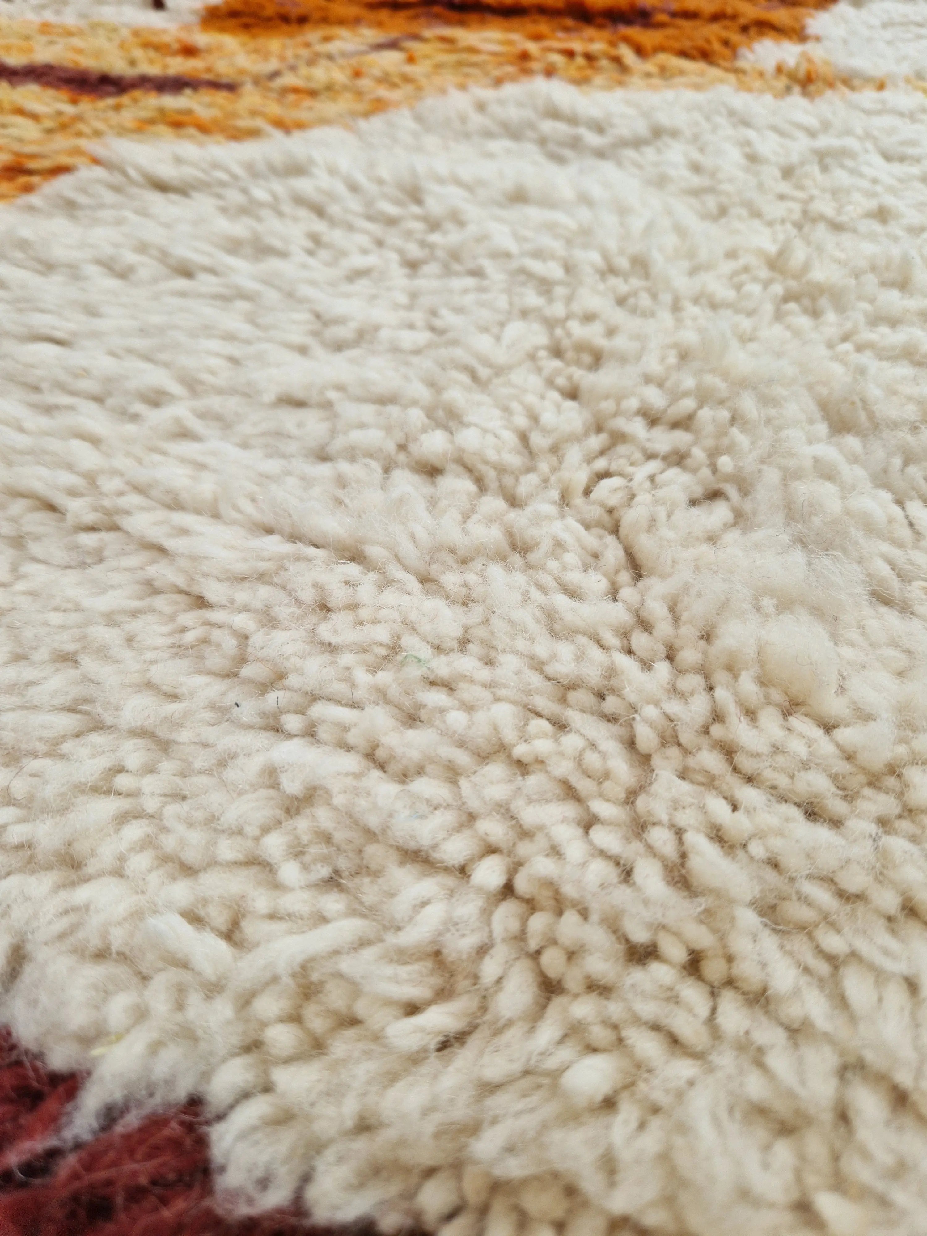 Sublimez votre intérieur avec ce tapis berbère authentique, noué à la main en laine naturelle. Ses motifs colorés sur fond ivoire, son épaisseur généreuse et son charme artisanal en font une pièce unique idéale pour un salon, une chambre ou un bureau chaleureux.