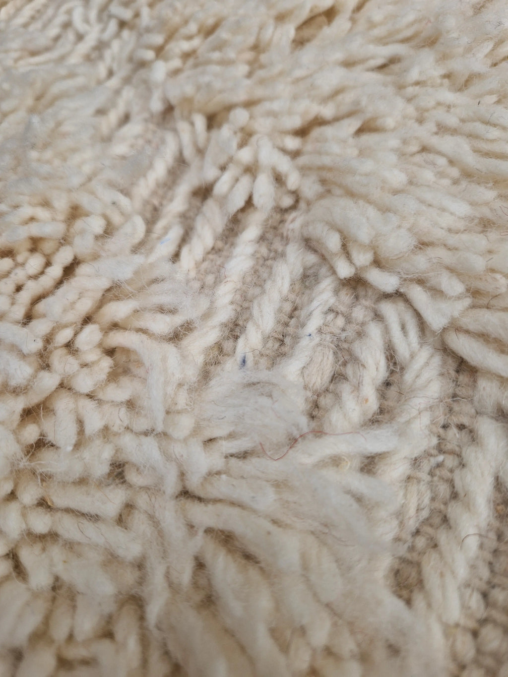 Tapis berbère Beni Ouarain en laine naturelle, tissé à la main au Maroc. Motifs en relief, douceur épaisse et charme artisanal. Pièce unique et chaleureuse.