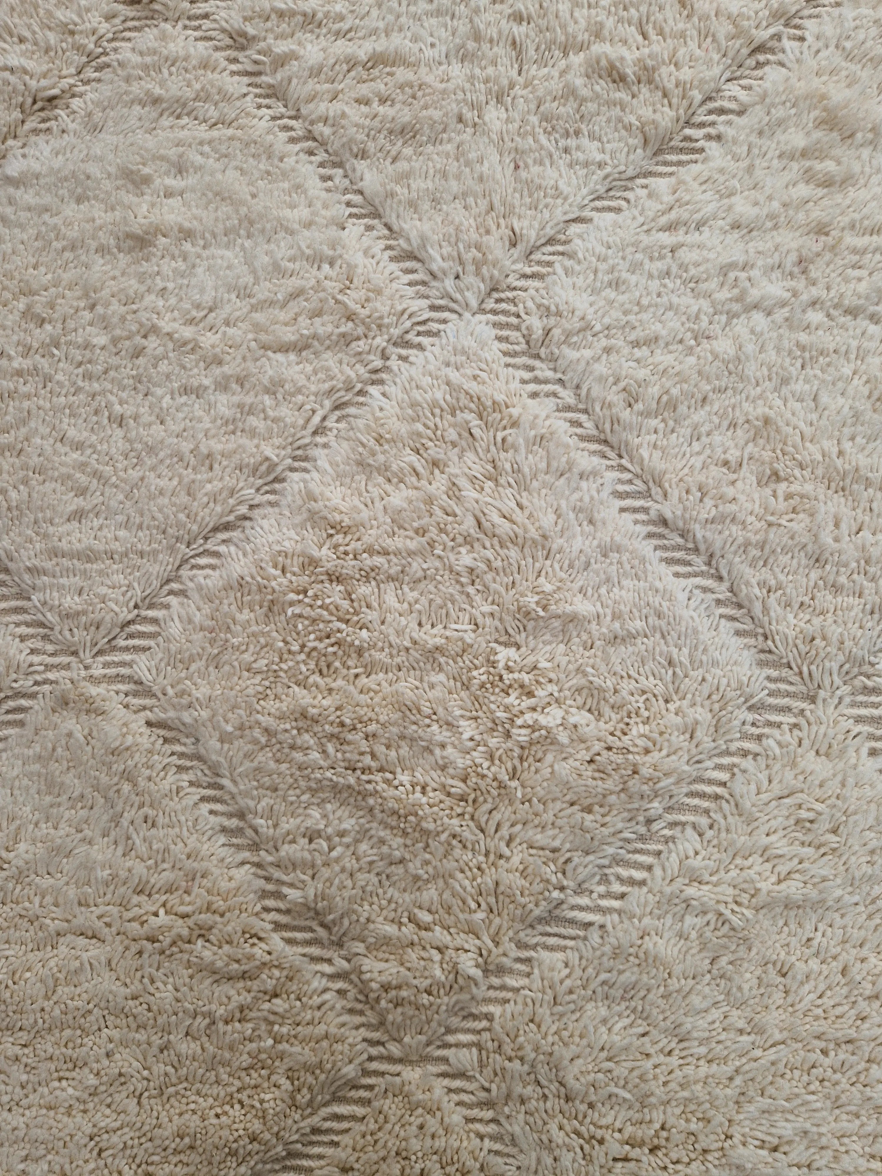 Tapis berbère Beni Ouarain en laine naturelle, tissé à la main au Maroc. Motifs en relief, douceur épaisse et charme artisanal. Pièce unique et chaleureuse.