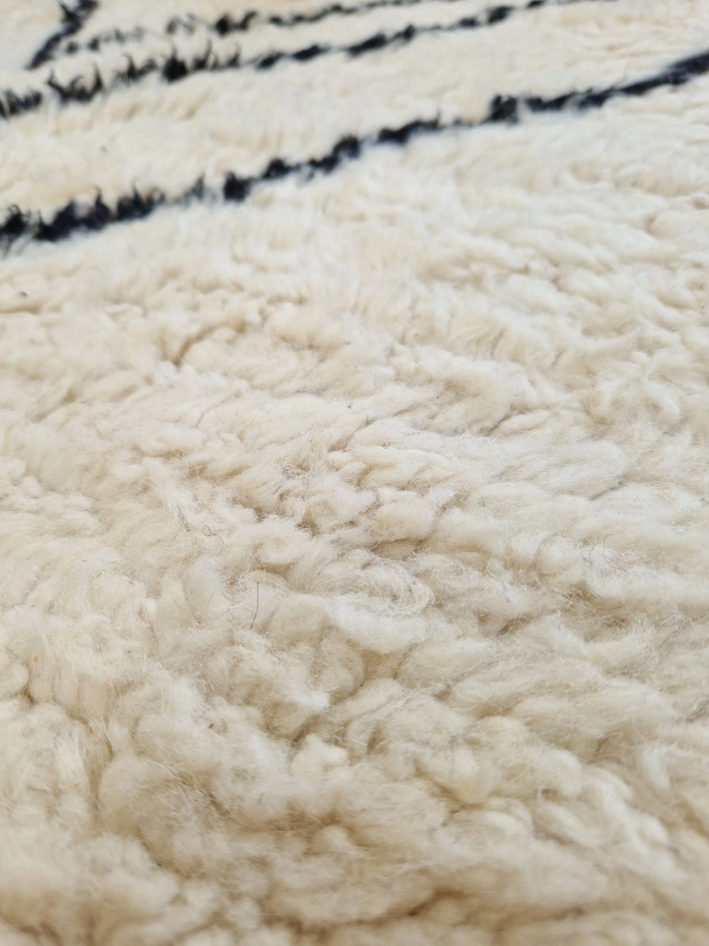 Tapis berbère beni ouarain en laine naturelle, tissé à la main au Maroc. Motifs colorés, douceur épaisse et charme artisanal. Pièce unique et chaleureuse.