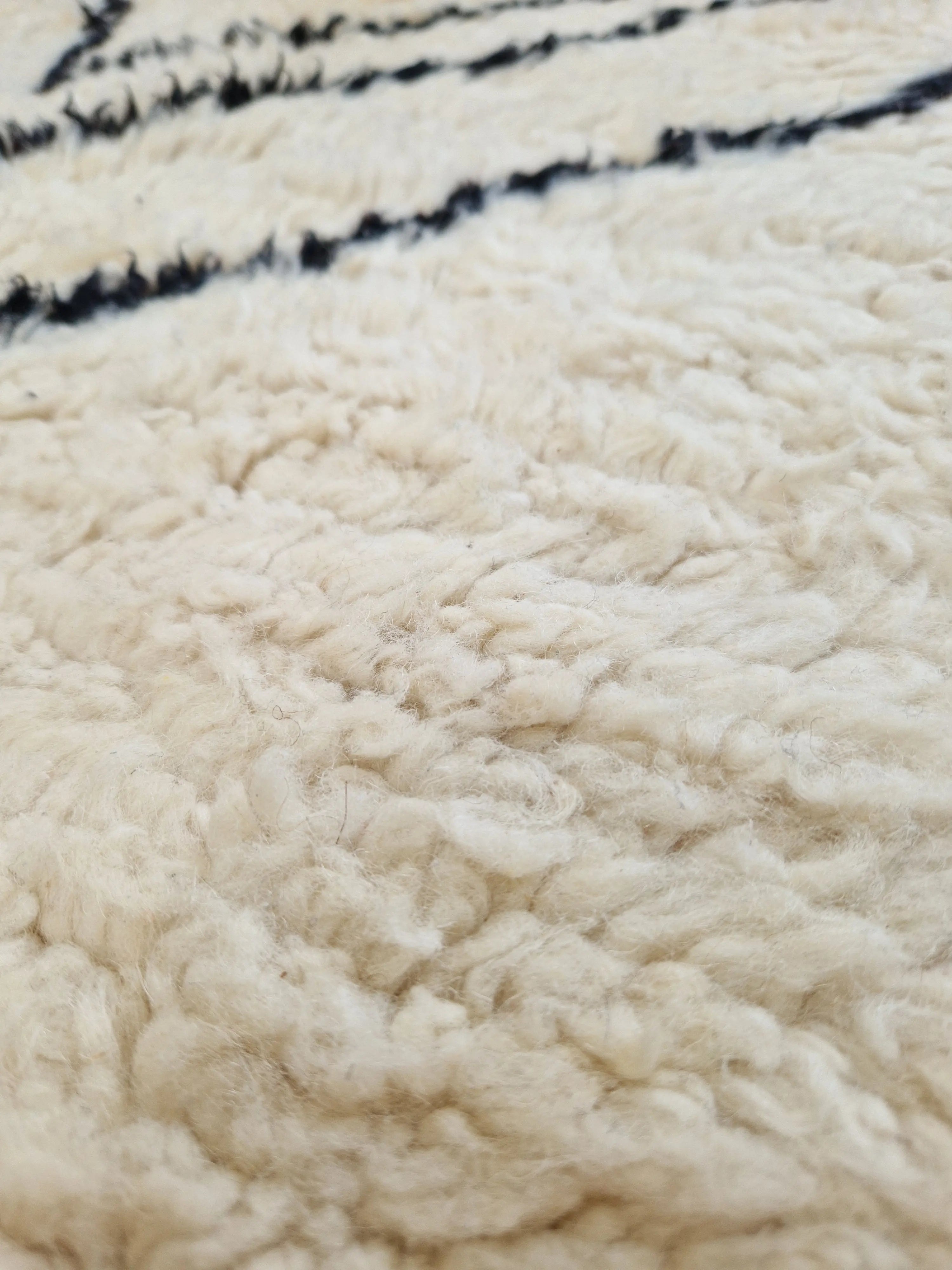 Tapis berbère beni ouarain en laine naturelle, tissé à la main au Maroc. Motifs colorés, douceur épaisse et charme artisanal. Pièce unique et chaleureuse.