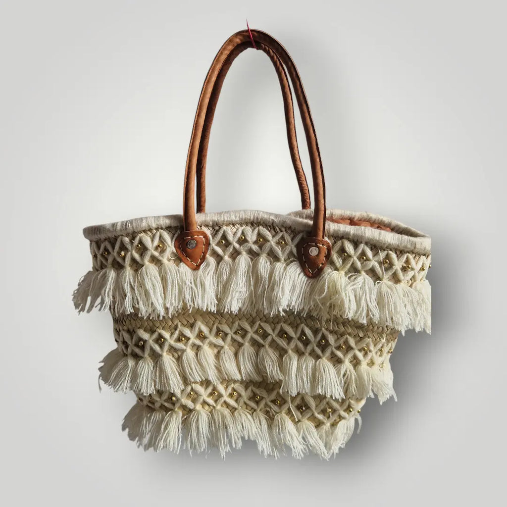 Panier tressé en feuilles de palmier, avec des poignée en cuir, et des franges en fil. Peut être utilisé en sac à main, en panier pour les courses, pour aller à la plage...