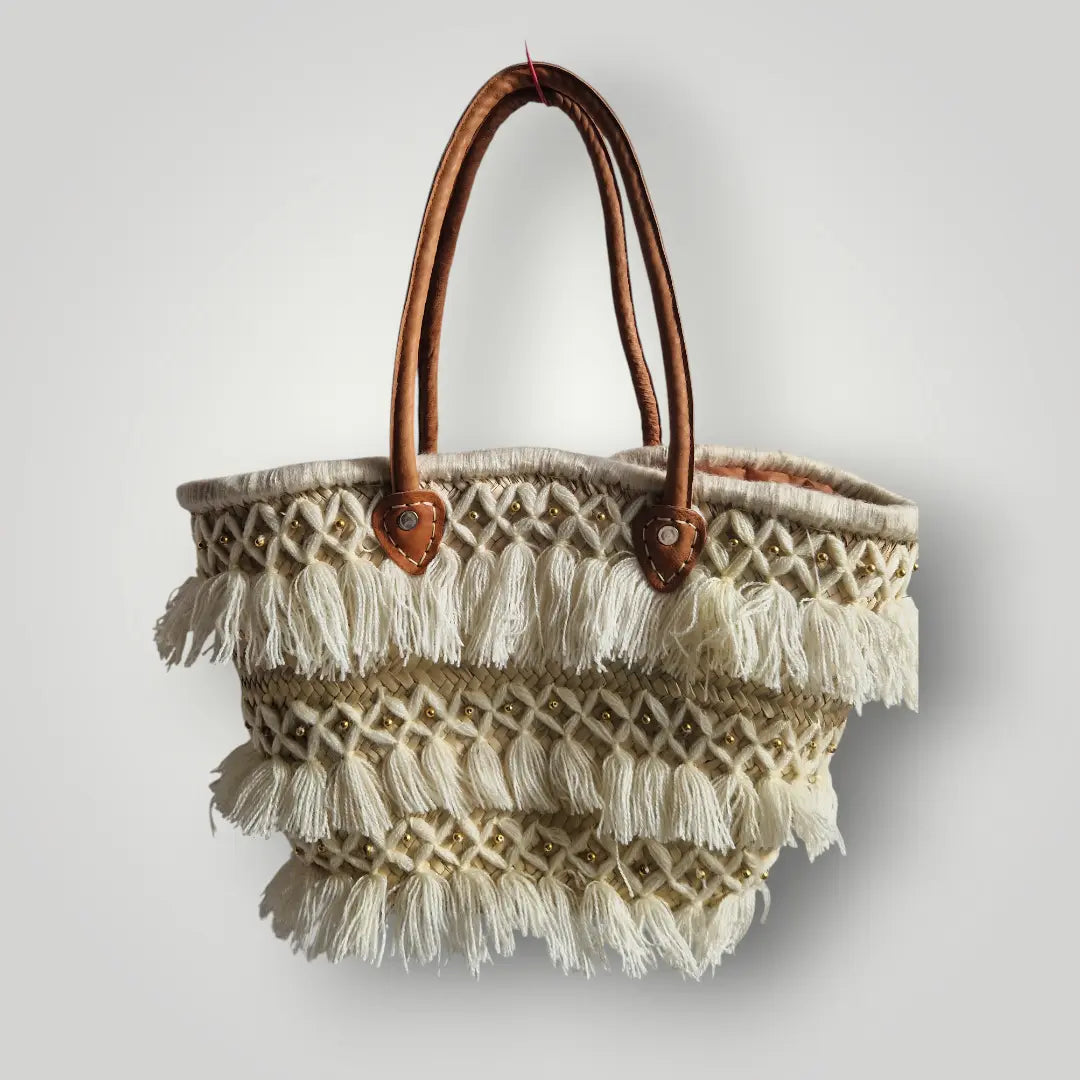Panier tressé en feuilles de palmier, avec des poignée en cuir, et des franges en fil. Peut être utilisé en sac à main, en panier pour les courses, pour aller à la plage...