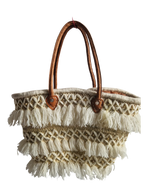 Panier tressé en feuilles de palmier, avec des poignée en cuir, et des franges en fil. Peut être utilisé en sac à main, en panier pour les courses, pour aller à la plage...